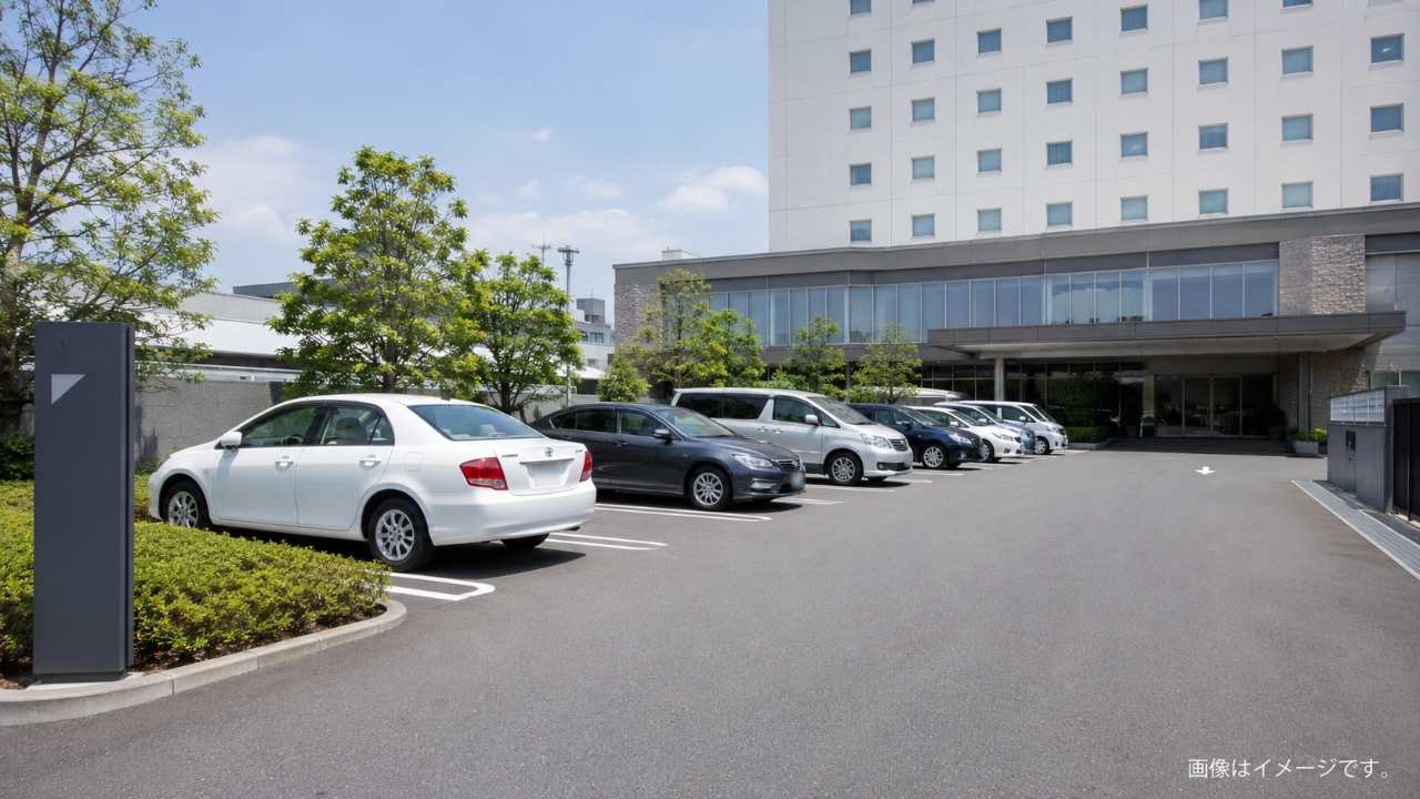 ホテル敷地内駐車場に普通車が整然と停まっているイメージ